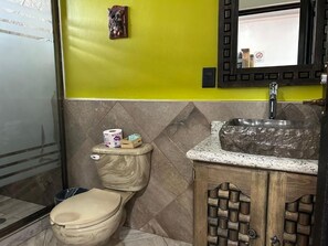 Ένα μπάνιο με τουαλέτα, νιπτήρα και καθρέφτη.