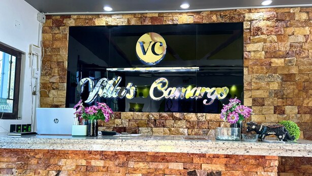 Una mesa de recepción con un fondo de pared de piedra, un logotipo y un cartel que dice 'Villa's Canarios'.