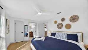 Un dormitorio con una cama grande, un ventilador de techo y decoración en las paredes.