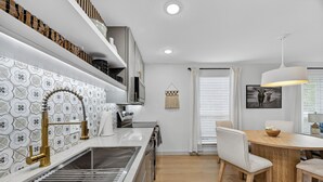 Una cocina moderna con un salpicadero de diseño, horno empotrado y comedor con mesa y sillas de madera.