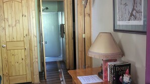 A wooden interior with a bench, a table with books and a gnome figurine, and a framed picture on the wall. - Pinetop Vista - The Wildlife Cabin (Pinetop)