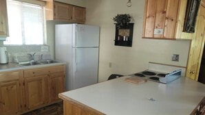 A compact kitchen with wooden cabinets, a white refrigerator, a sink, and a stove. - Pinetop Vista - The Wildlife Cabin (Pinetop)