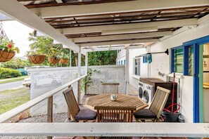 A covered outdoor area with a table and chairs, a washing machine, and hanging planters. - Self contained studio near the boat club with deck (Yorkeys Knob)