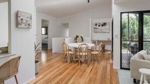 Een modern interieur met een eethoek, een bank en een balkon met buitenmeubilair.