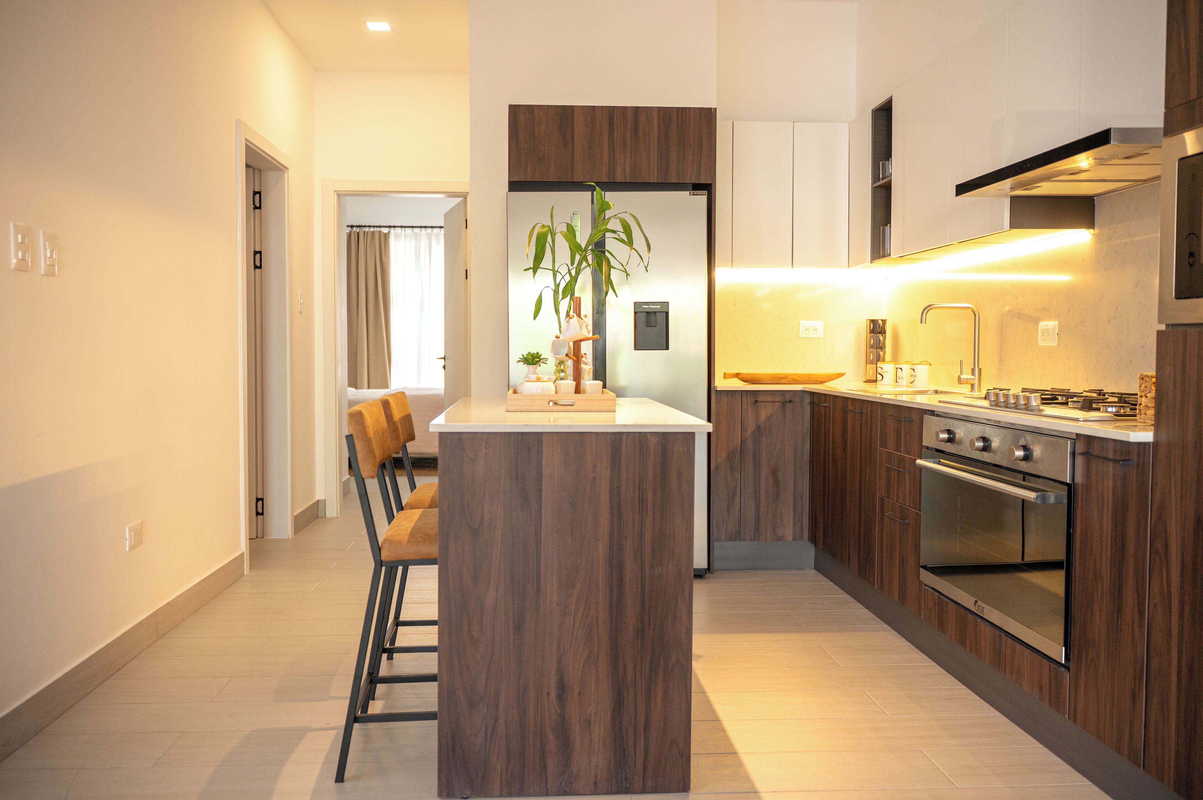 A modern kitchen with a central island, wooden cabinets, and a built-in oven.