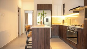 Een moderne keuken met een centraal eiland, houten kastjes en een ingebouwde oven.