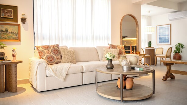 Een woonkamer met een bank, een rond salontafeltje en een eethoek met stoelen en een tafel.