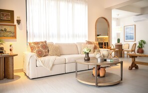 Ein Wohnzimmer mit einer Couch, einem runden Couchtisch und einem Essbereich mit Stühlen und einem Tisch.