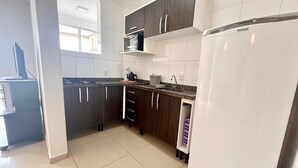 A modern kitchen with dark wooden cabinets, a white refrigerator, and a microwave. - Beautiful apartment located on Bombas Beach 🐶️ Sleeps up to 8 people (Bombinhas)