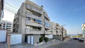 A multi-story residential building with balconies, a gated entrance, and a paved street. - Beautiful apartment located on Bombas Beach 🐶️ Sleeps up to 8 people (Bombinhas)