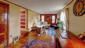 Ein Wohnzimmer mit einer Couch, einem Couchtisch, einer Uhr und einem großen Fenster.