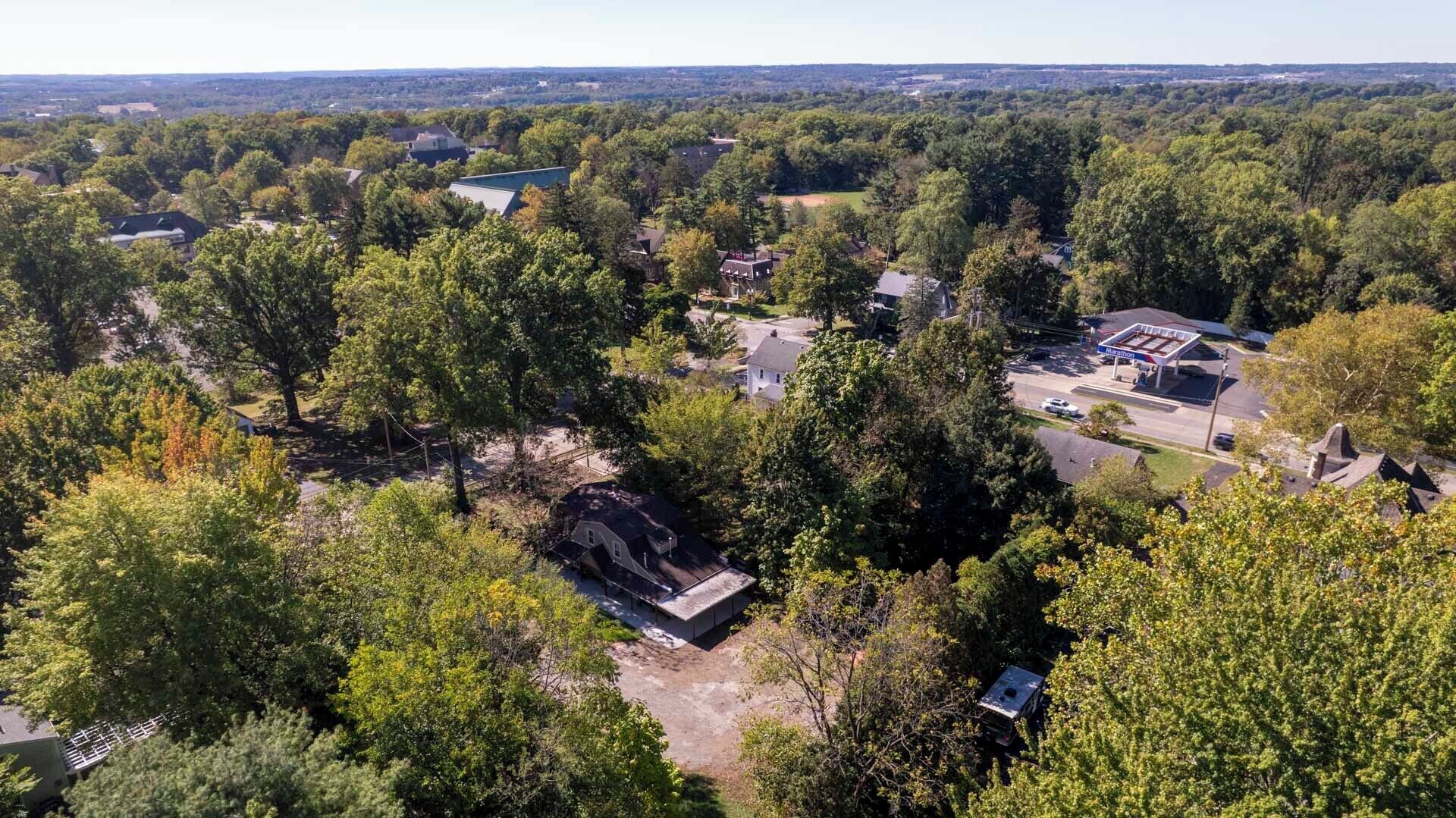Vue aérienne d’un quartier résidentiel avec des maisons, une station-service et une végétation luxuriante.