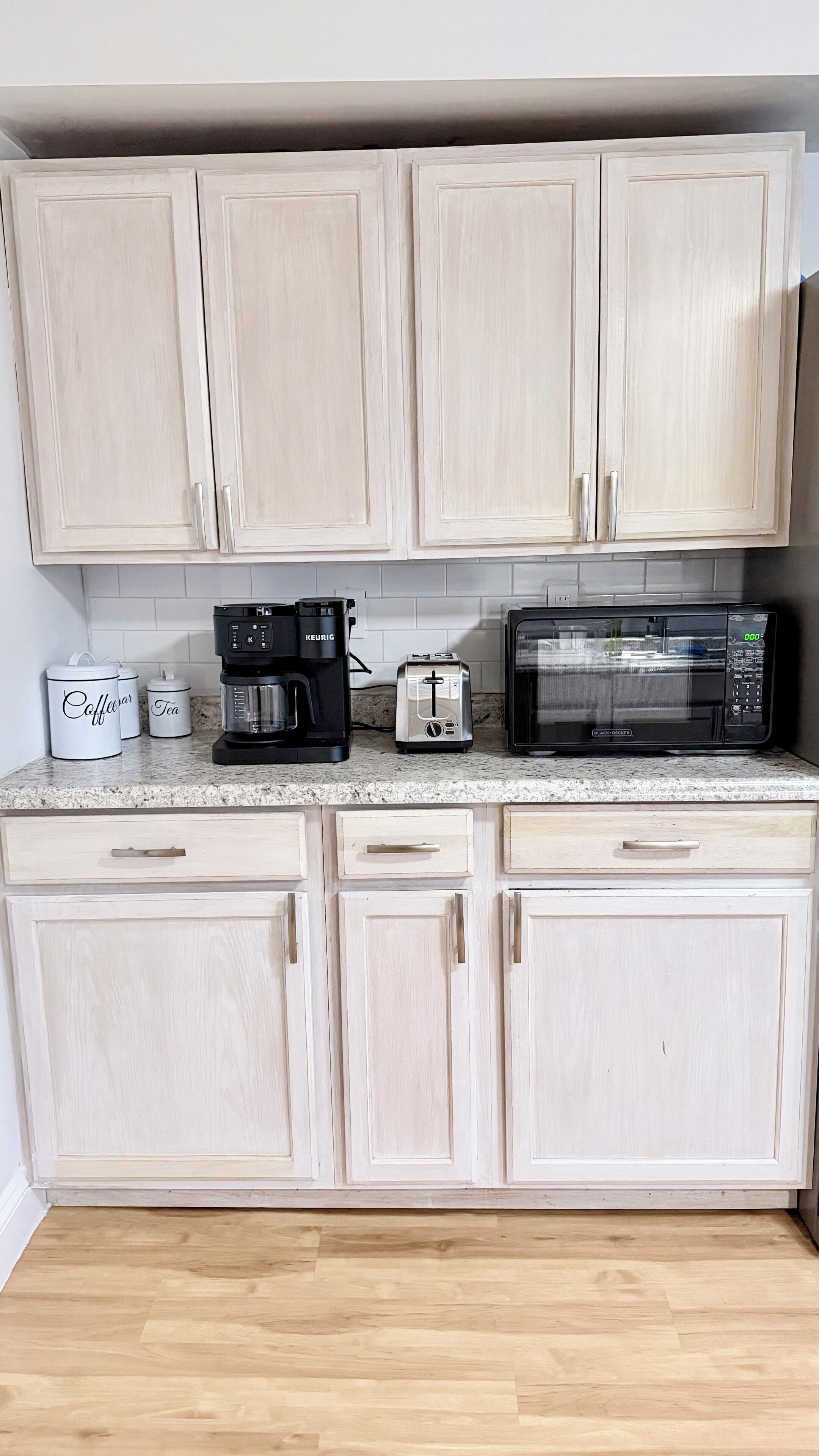 A kitchen with light wooden cabinets, a coffee maker, a toaster, and a microwave.