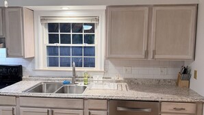 Una cocina con encimera de granito, pileta de acero inoxidable y muebles de madera.
