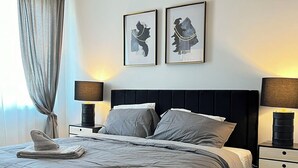 Ein modernes Schlafzimmer mit einem großen Bett, zwei Nachttischen und einem Beistelltisch.