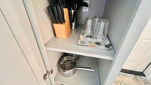 Une cuisine équipée d’un bloc à couteaux, d’une machine à café et d’une casserole posée sur le plan de travail.