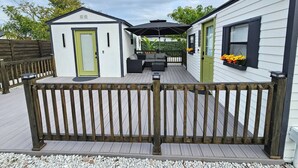 Une maison mobile dotée d’une terrasse, d’un petit porche et d’un espace clôturé.