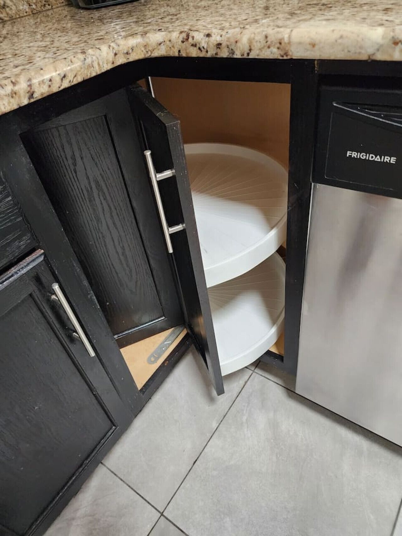 A kitchen with a built-in dishwasher and a double-tiered white shelf unit.