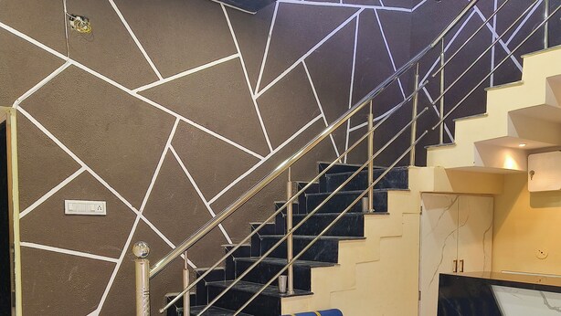 Um interior moderno com um sofá azul, uma escada com design geométrico na parede e um chão de mármore.