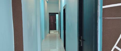 A hallway with a marble floor, light blue walls, and a dark blue door at the end.