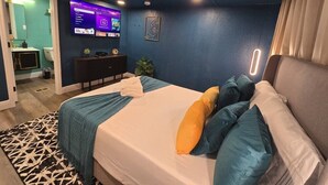 Een moderne hotelkamer met een groot bed, een tv aan de muur en een klein bureau met een plant.