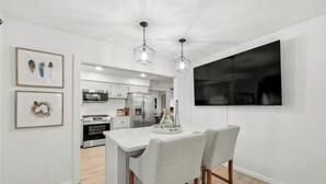 Una cocina moderna con armarios blancos, una isla central e iluminación colgante.