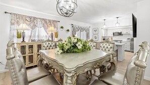 Un comedor con una amplia mesa ornamentada, sillas acolchadas y un candelabro.