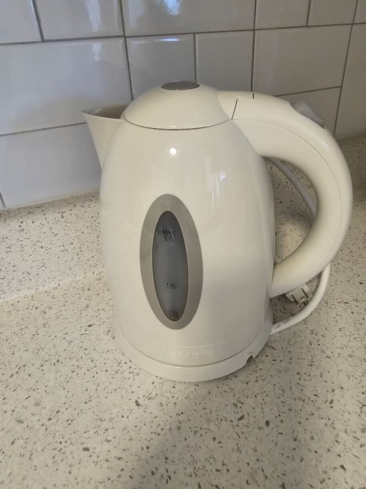 A white electric kettle with a digital display on a speckled countertop.