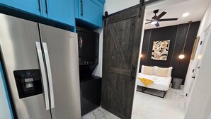 Eine moderne Küche mit einem Edelstahlkühlschrank, einer Mikrowelle und einer dunklen Holztür.