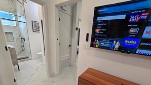 Ein modernes Hotelzimmer mit einem großen Flachbildfernseher an der Wand, der die Roku TV-Oberfläche anzeigt.
