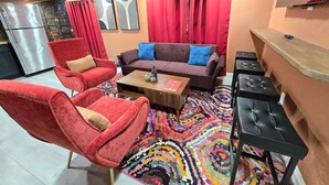 Ein Wohnzimmer mit einer Couch, zwei Sesseln, einem Couchtisch und einem gemusterten Teppich.