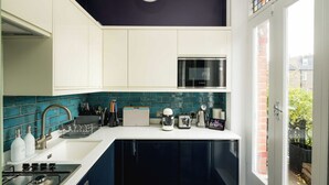 Una cucina moderna con mobili bianchi, un microonde Bosch, un fornello a gas e una macchina per il caffè.