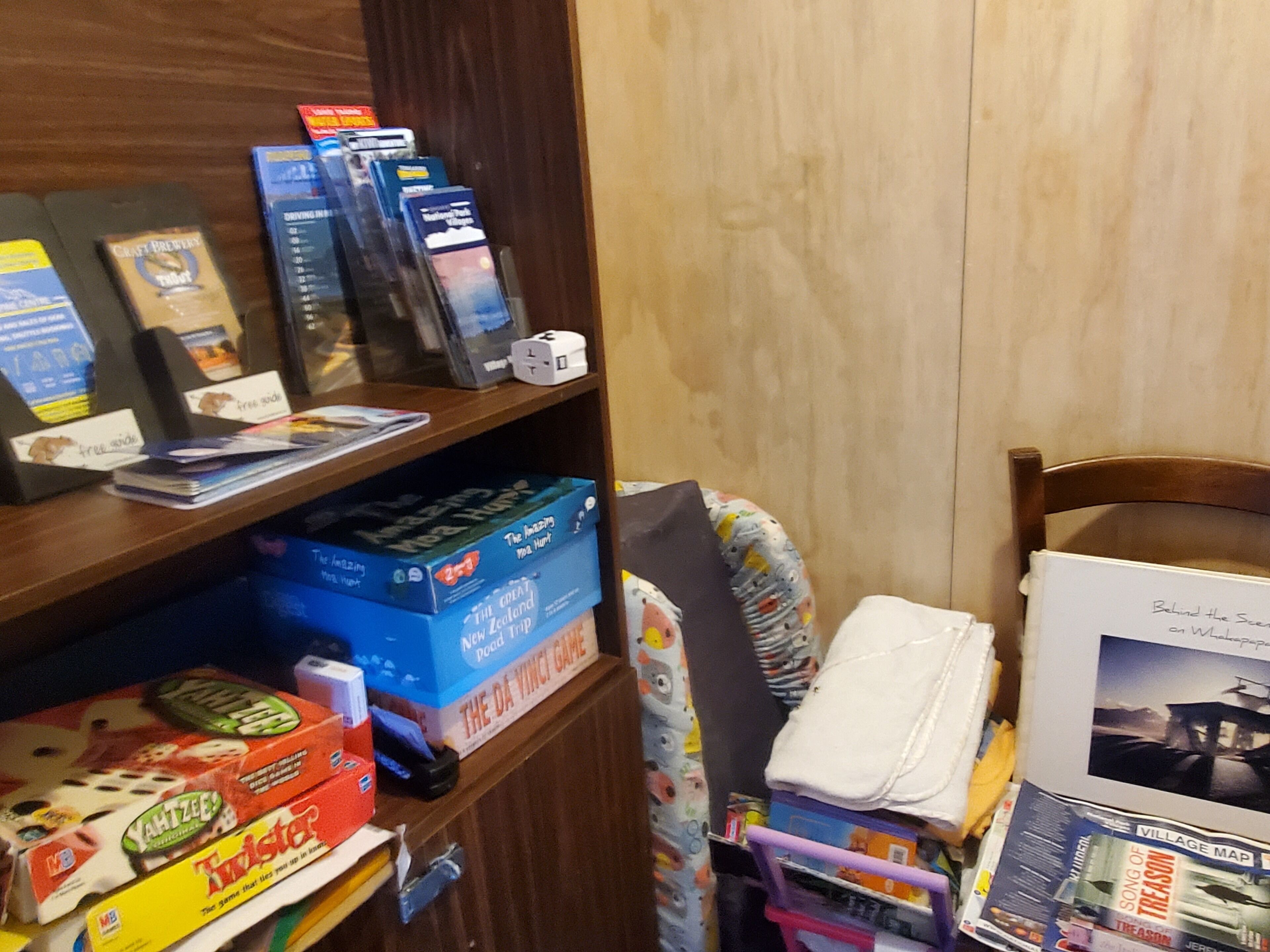 Une étagère avec des jeux de société et des guides de voyage.