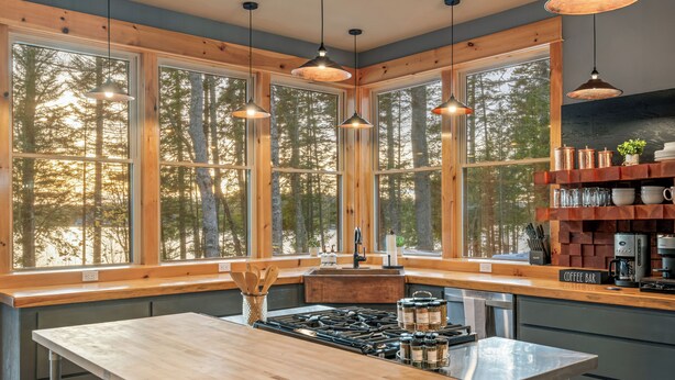 A modern kitchen with large windows, wooden countertops, and a coffee bar. - Spacious 5-Bedroom -Hot Tub, MDI, Lake front, Fire pit, Game Room, Dog Friendly! (Franklin)