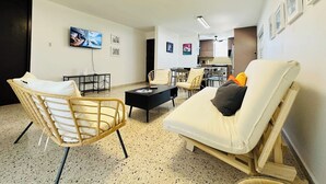 Una sala de estar moderna con un sofá, sillas, una mesa de centro y un televisor montado en la pared.