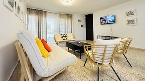 Una sala de estar con un sofá, dos sillones, una mesa de centro y un televisor.