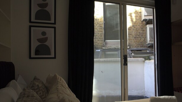 Un dormitorio con una cama, una ventana y vista a un edificio de ladrillo.