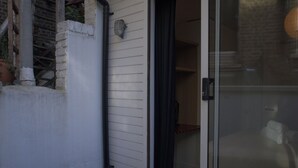 Un edificio residencial con un puerta corrediza de vidrio que da a una habitación con una cama y una silla.