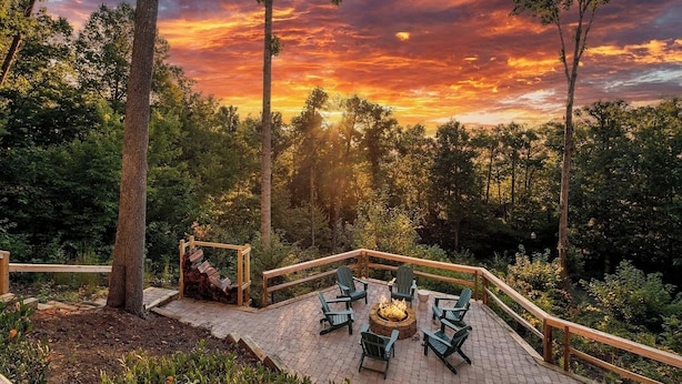 A deck with outdoor seating and a fire pit, surrounded by trees and a sunset view. - Hot Tub, Deck w/ Breathtaking Mountain Views (Swannanoa)