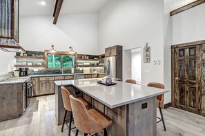 A modern kitchen with a large island, wooden cabinets, and a rustic door. - The Emerald Palace in Angel Fire (Angel Fire)