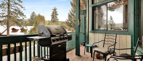 A covered outdoor area with a grill, a gas tank, and a chair.