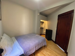 Een slaapkamer met een bed, een kledingkast en een klein bureau.