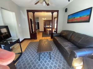 A living room with a leather sofa, a coffee table, and a television. - Sweet 2-bedroom + den apartment with AC in vibrant Bucktown (Chicago)