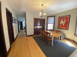 A dining area with a wooden table and chairs, a chandelier, and a poster on the wall. - Sweet 2-bedroom + den apartment with AC in vibrant Bucktown (Chicago)