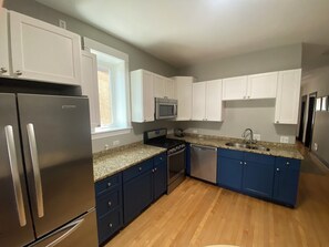 Una cocina moderna con electrodomésticos de acero inoxidable, encimeras de granito y armarios azules.