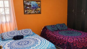 Ein Zimmer mit zwei Betten, einer Klimaanlage, einem Deckenventilator und einem Bild an der Wand.