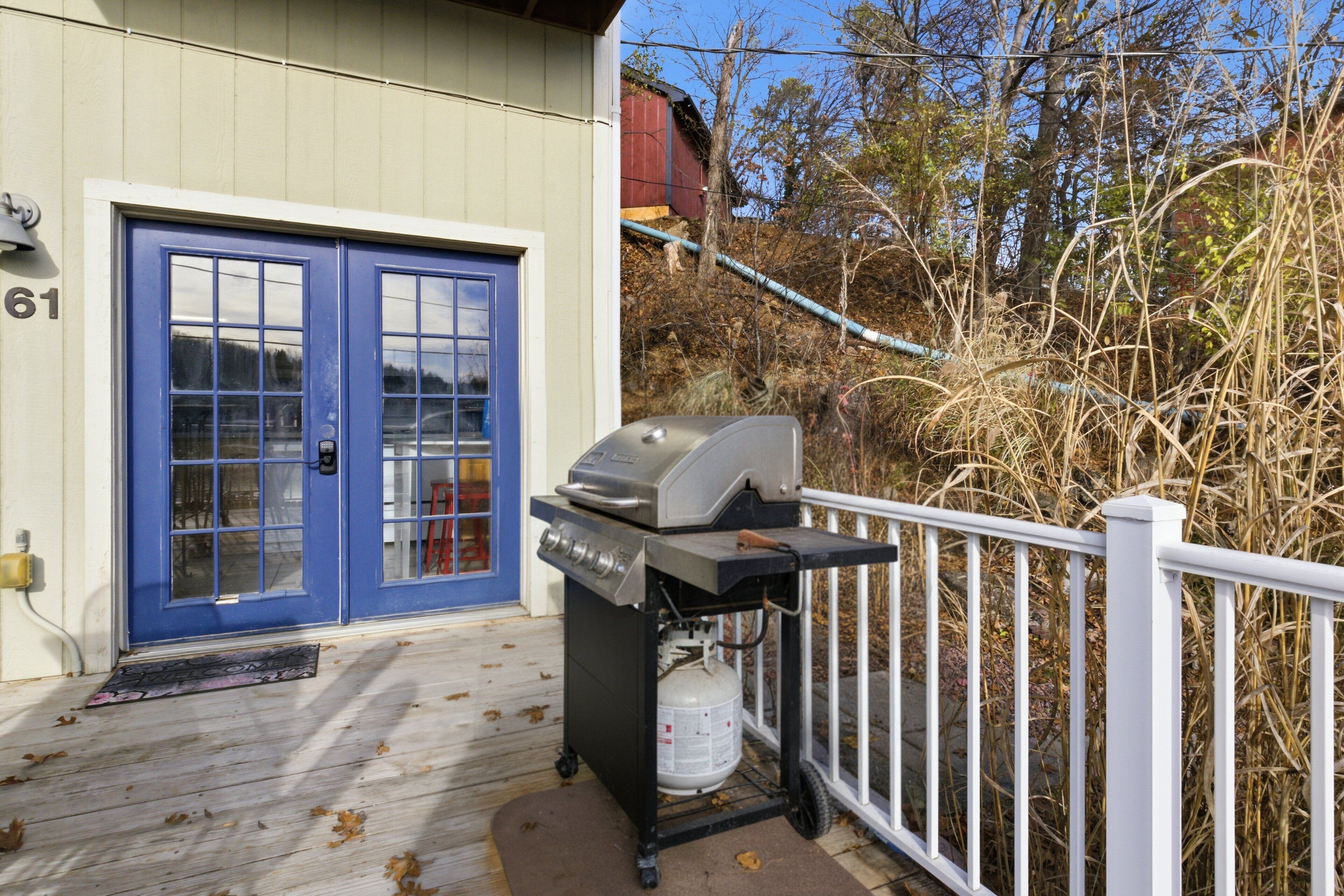 A blue door with a number '61' on the wall, a barbecue grill with a propane tank, and a white railing.