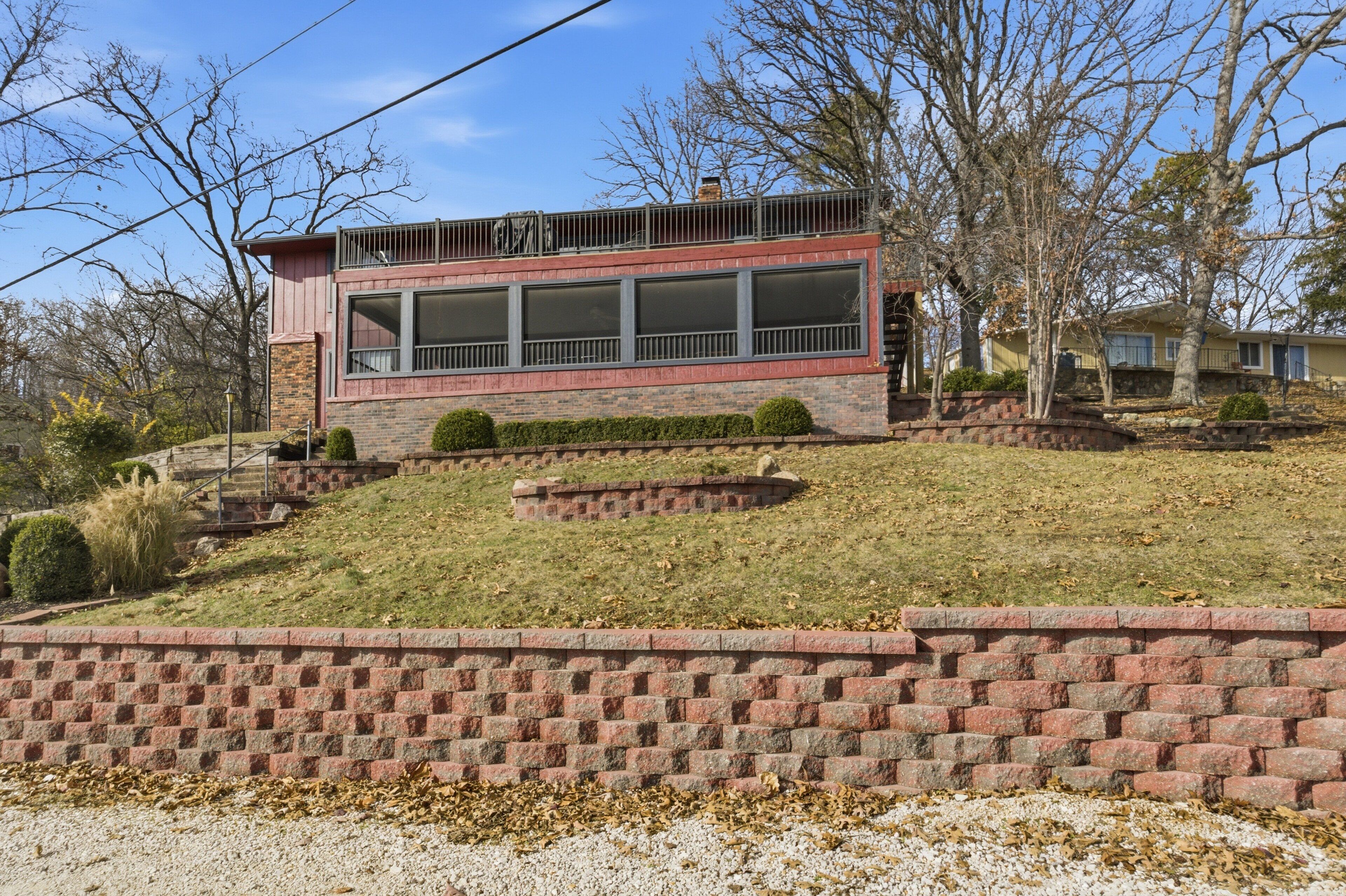 A modern two-story house with a flat roof, large windows, and a brick exterior.