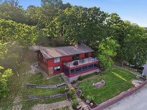 A two-story house with a red exterior, a balcony, and a garage. - Lakefront Home w/ Decks & Docks at Shorty Pants Bar 21mm (Osage Beach)