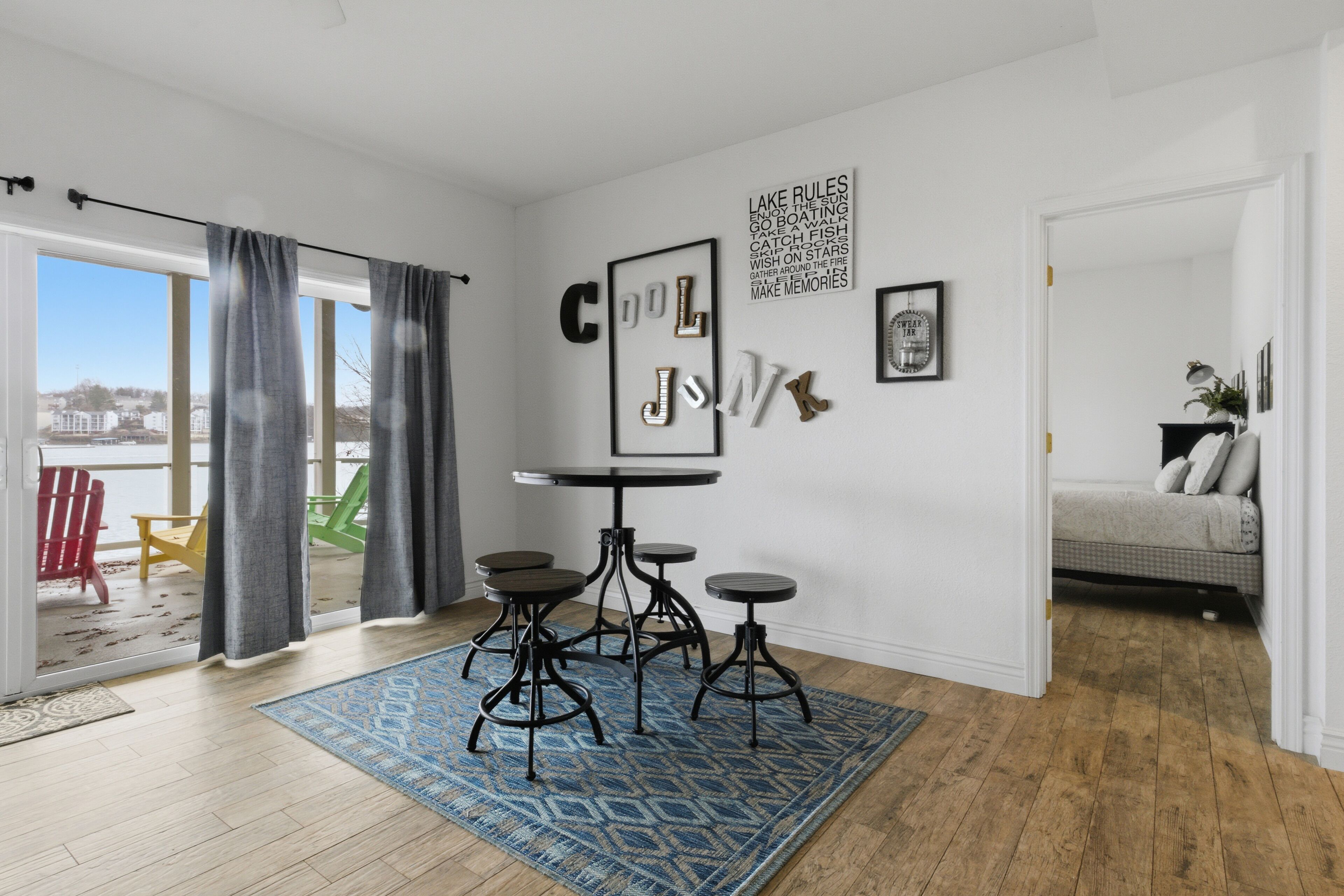 Una sala de estar moderna con un ventanal grande, una zona de comedor con mesa y taburetes, y un rincón de descanso acogedor con un sofá.